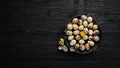 Quail eggs in a black plate. On the old background. Royalty Free Stock Photo