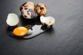 Quail eggs on black stone background, broken, cracked quail egg, yolk of quail egg. Royalty Free Stock Photo