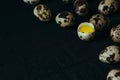 Quail eggs on a black textured background. Raw broken egg with the yolk. Easter card. Side view. Royalty Free Stock Photo
