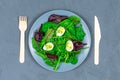 Quail eggs boiled on a lettuce leaf with microgreen sprouts with a wooden fork and spoon on a gray background. The Royalty Free Stock Photo