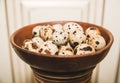 Quail eggs are in the brown ware on the light background