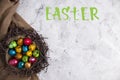 Quail eggs for the easter holiday. Colorful eggs in a nest on a light background. Copy space, top view. Letteing Happy