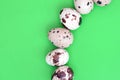 Quail eggs on a light green surface, top view, empty place for t