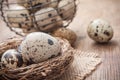 Quail eggs in nest on wooden table with metallic bask