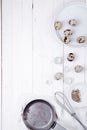 Quail eggs in a plate, a shell, a whisk for beating and a frying pan on a white wooden background. view from above Royalty Free Stock Photo