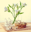 Quail eggs with straw and feathers in basket, white hares on bur Royalty Free Stock Photo