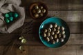 Quail eggs in teal colored plate, colored eggs, emply egg shells on wooden rustic background. Easter scene