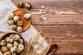 Quail eggs in a wooden bowls and plates with broken eggshell on a rustic table linen with ears of wheat and wooden spoon Royalty Free Stock Photo