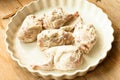 Quails plucked raw ready for cooking in sour cream on white plate on wooden background close up