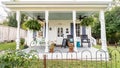 Quaint cottage with an inviting porch featuring outdoor furniture and potted plants