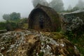 Quaint Toda tribe hut in a green foggy landscape. Tamil Nadu, India