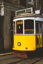 Quaint yellow tram on the rails of old and beautiful street of Alfama District of Lisbon. City touristic landmarks of Royalty Free Stock Photo