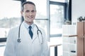 Qualified confident doctor feeling good himself and smiling. Royalty Free Stock Photo