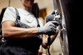 A qualified young mechanic changing a tire of a lifted car. Repair workshop