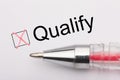 Qualify - checkbox with a cross on white paper with pen. Checklist concept
