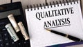 QUALITATIVE ANALYSIS - words in a notebook on the background of a calculator and banknotes Royalty Free Stock Photo