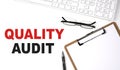 QUALITY AUDIT text written on white background with keyboard, paper sheet and pen