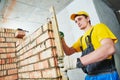 Bricklaying. Worker checks erected brick wall with level