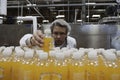 Quality control worker checking juice bottle on production line