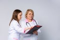 Quality medical services. Female doctors in uniform taking notes to clipboard while standing in hospital corridor. Medical Royalty Free Stock Photo