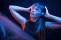 Quality music in headphones. Studio shot in dark studio with neon light. Portrait of young girl Royalty Free Stock Photo