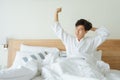 Quality of sleeping and waking or getting up concept. Asian man in bathrobe and towel, waking up on white bed in hotel bedroom in Royalty Free Stock Photo