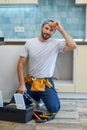 Quality work. Attractive young handyman, plumber wearing tool belt smiling at camera while holding a pipe wrench, ready Royalty Free Stock Photo