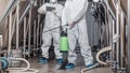 Workers in protective suits with spray bag and tablet in factory Royalty Free Stock Photo