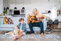 Quarantine Family time: Little and older brothers at living room together.Teen playing acoustic guitar, smiling little boy playing Royalty Free Stock Photo