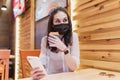 Quarantine rate in a cafe, a young woman in a black mask. Royalty Free Stock Photo