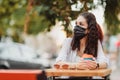 Quarantine rate in a cafe, a young woman in a black mask. Royalty Free Stock Photo
