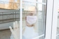 Coronavirus. Sick woman wearing protection face mask looking through the window. Patient isolated in house to prevent Royalty Free Stock Photo