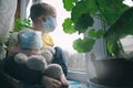 Quarantine, threat of coronavirus, virus protection, pandemic. Child and his teddy bear both in protective masks sits on