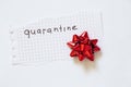 Quarantine word on a piece of paper and a gift red bow on an isolated background Royalty Free Stock Photo