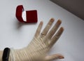 Quarantined wedding.coronavirus wedding.hand in a medical glove with a wedding ring on a white background next to a red