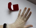 Quarantined wedding.coronavirus wedding.hand in a medical glove with a wedding ring on a white background next to a red