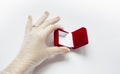 Quarantined wedding.coronavirus wedding.hand in a medical glove with a wedding ring on a white background next to a red