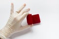 Quarantined wedding.coronavirus wedding.hand in a medical glove with a wedding ring on a white background next to a red