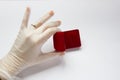 Quarantined wedding.coronavirus wedding.hand in a medical glove with a wedding ring on a white background next to a red