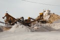 Quarry machines and piles of gravel over blue sky. Stone crushing and screening plant Royalty Free Stock Photo