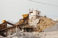 Quarry machines and piles of gravel over blue sky. Stone crushing and screening plant