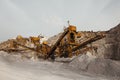 Quarry machines and piles of gravel over blue sky. Stone crushing and screening plant Royalty Free Stock Photo