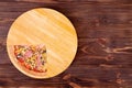 Quarter of pizza with chicken breast, corn, bacon and mushrooms, on a round wood plate which is on wooden rustic background Royalty Free Stock Photo