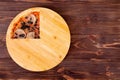 Quarter of pizza with ham, mozzarella, mushrooms and olives on a round wood plate which is on wooden rustic table Royalty Free Stock Photo