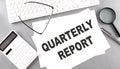 QUARTERLY REPORT ext on paper with keyboard, calculator on grey background Royalty Free Stock Photo