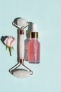 Quartz roller and Bottle of cometic product, rose serum or oil on a blue background. Cosmetics and tools. Skin care concept with