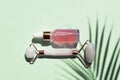 Quartz roller and Bottle of cometic product, rose serum or oil on a blue background. Cosmetics and tools. Skin care concept with