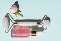 Quartz roller and Bottle of cometic product, rose serum or oil on a blue background. Cosmetics and tools. Skin care concept with