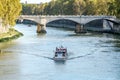 Quay of the river Tiber in Rome, a bridge and a group of foreign tourists on a boat tour and architectural monuments and the churc