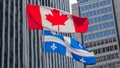 Quebec and Canada flags fluttering in the wind together in the downtown of Montreal.